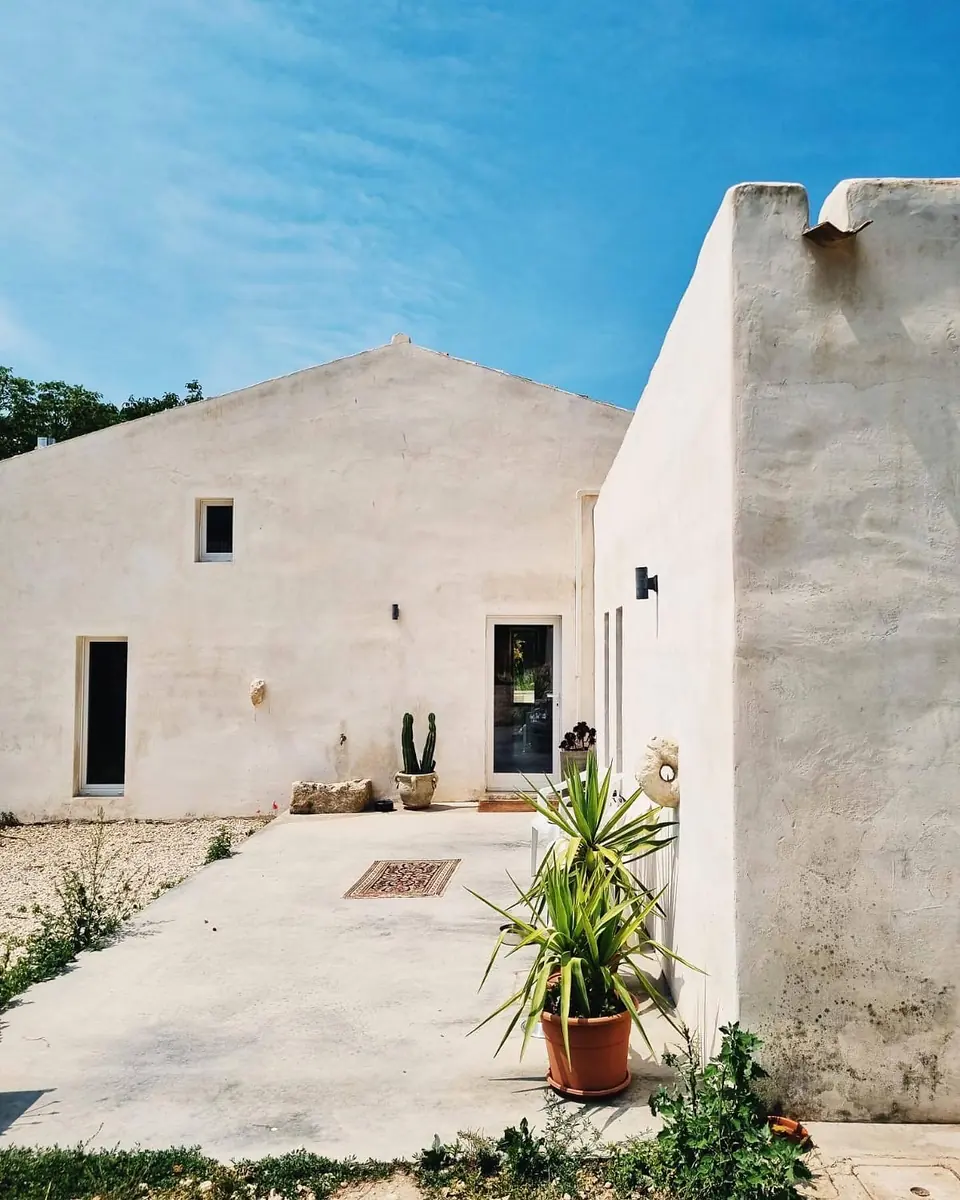 The white front of the farmhouse and its courtyard against a deep blue sky