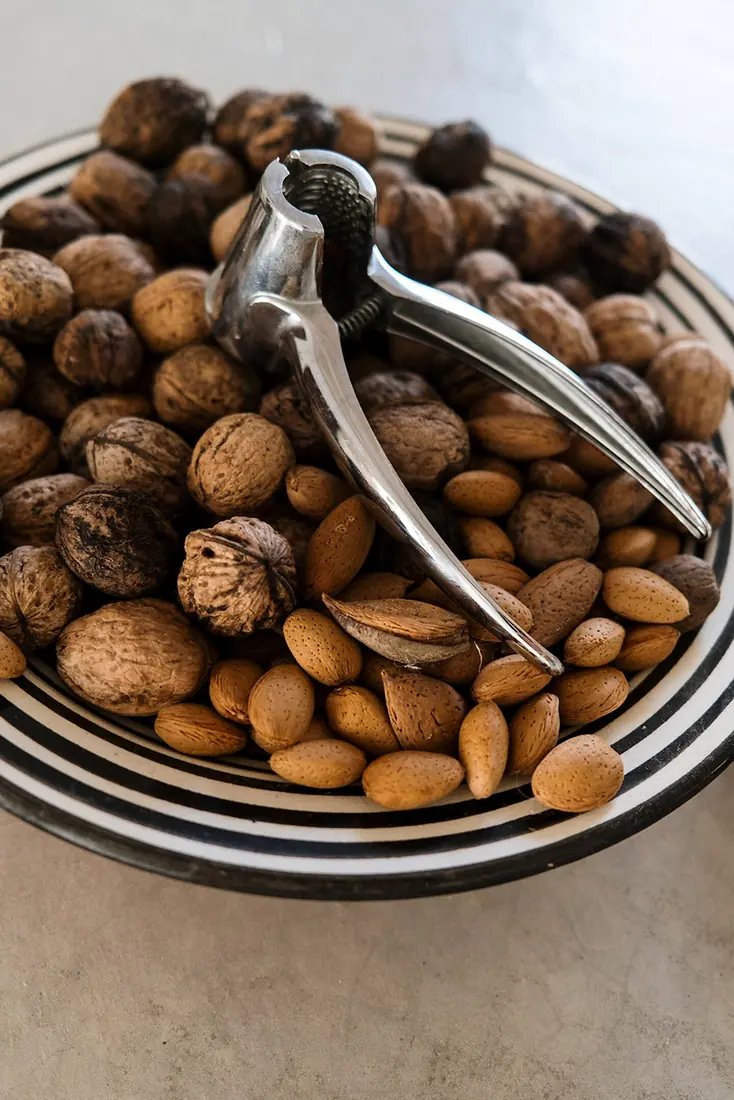 A bowl of our walnuts and almonds with an old steel nutcracker